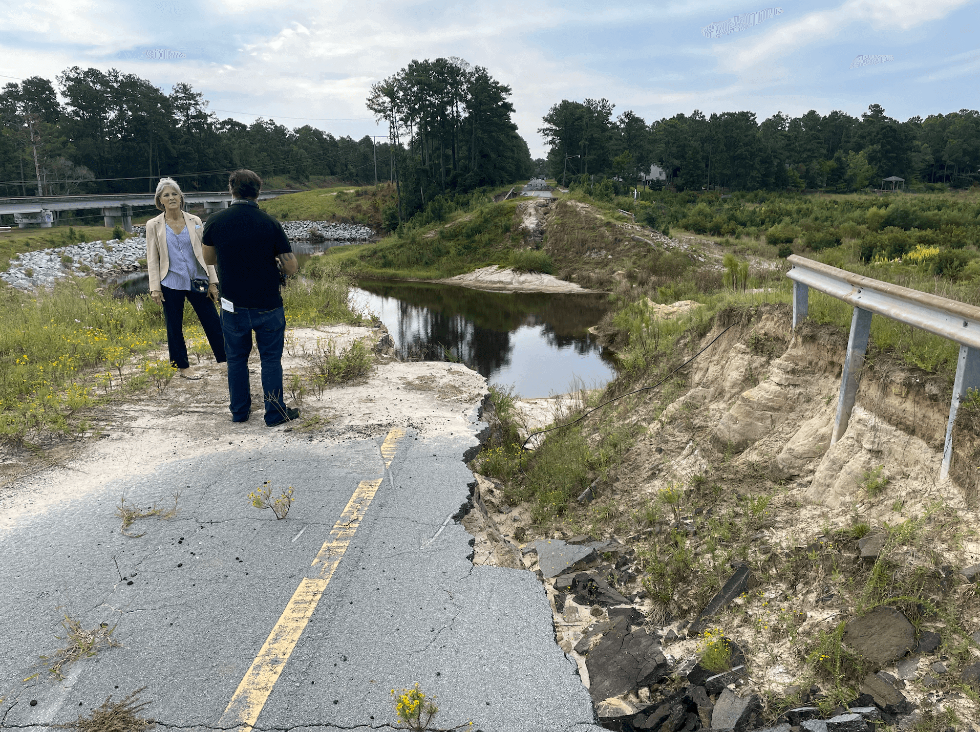 two people stand at ledge of destroyed road