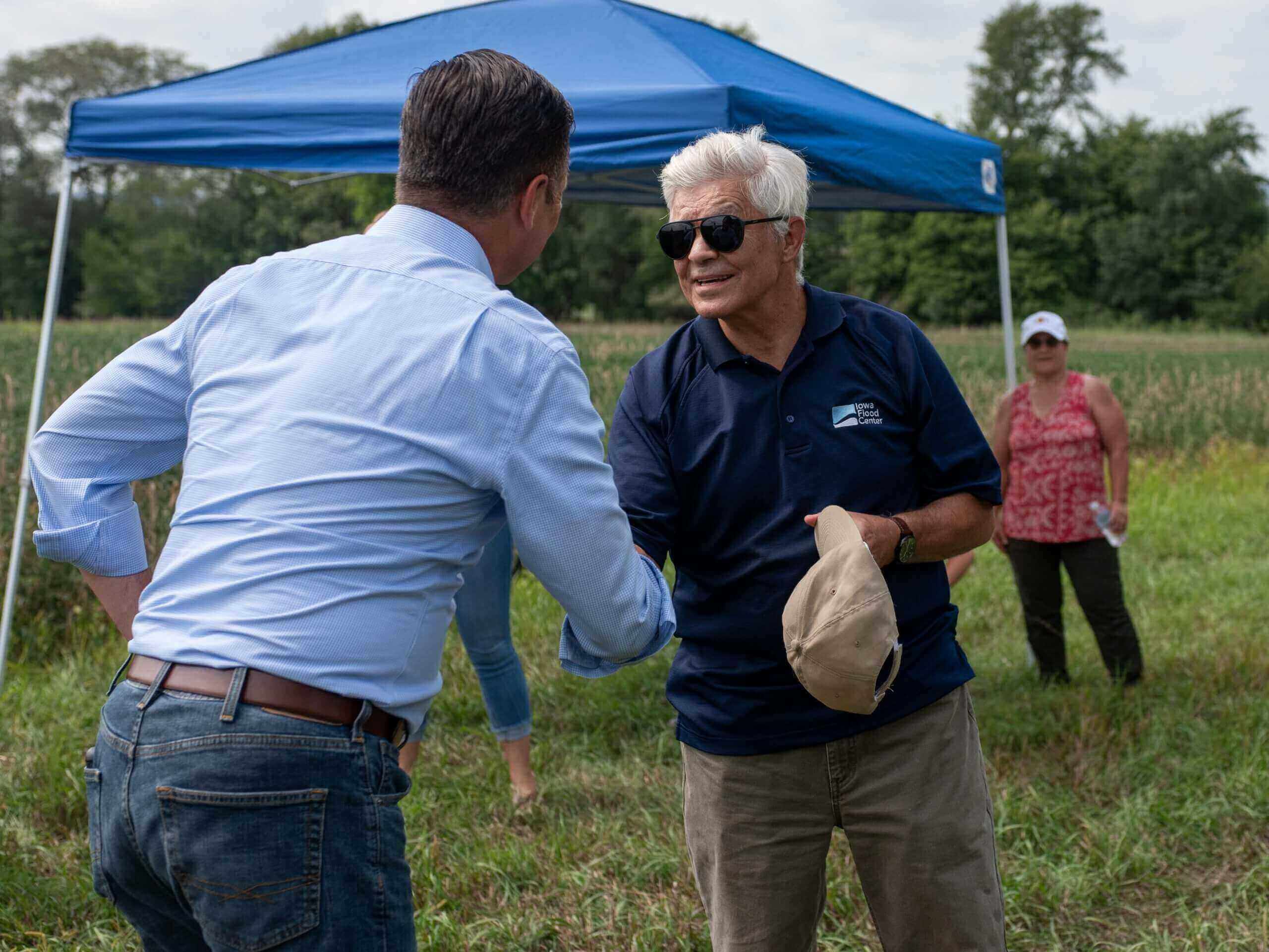 two men shaking hands in front of tent outside