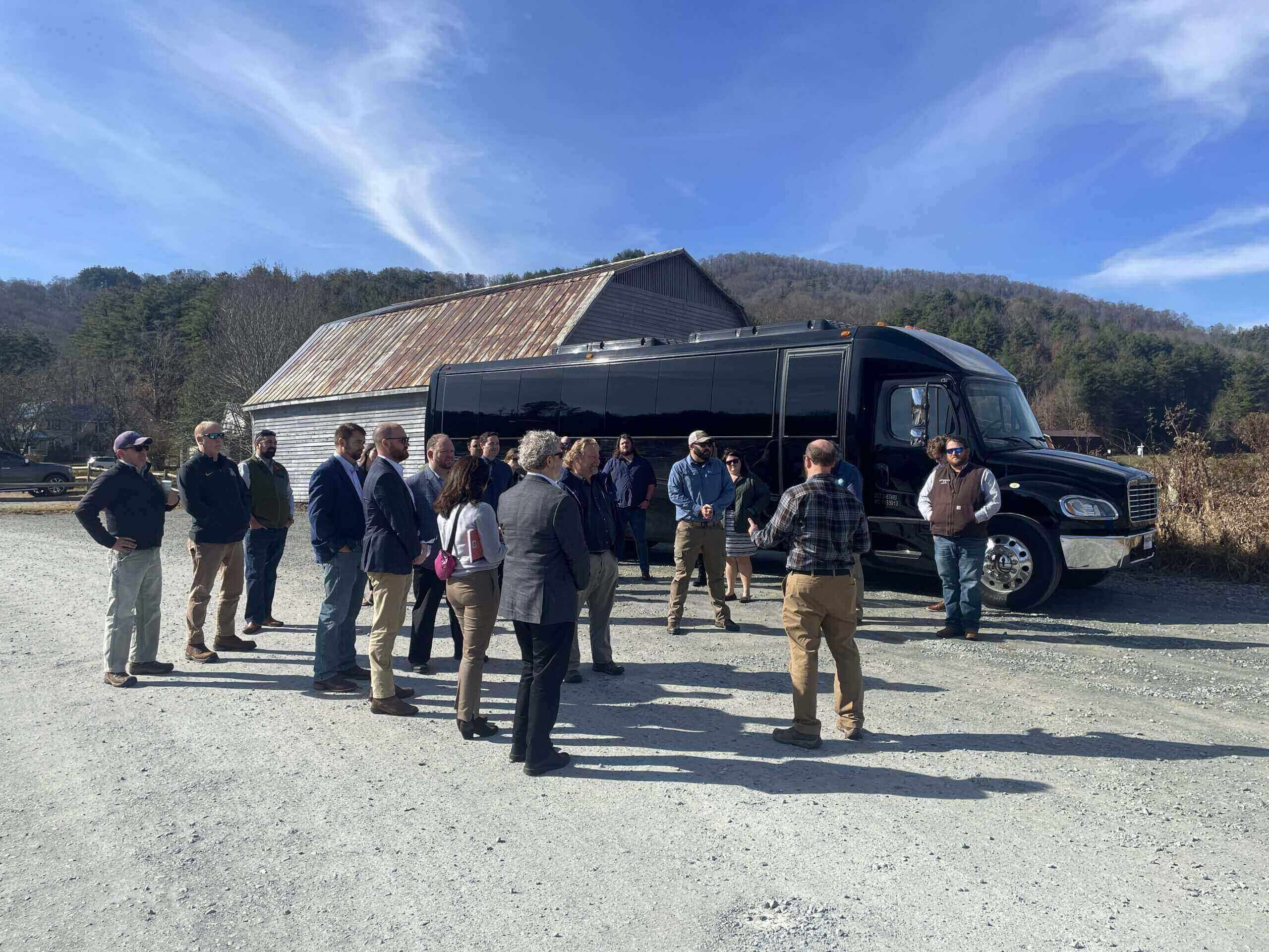 people standing in circle outside of a bus