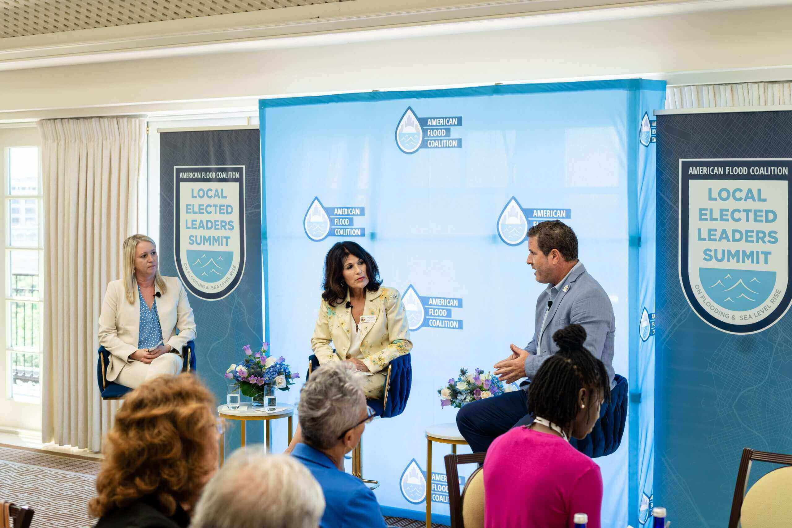 three people sitting at chairs on stage