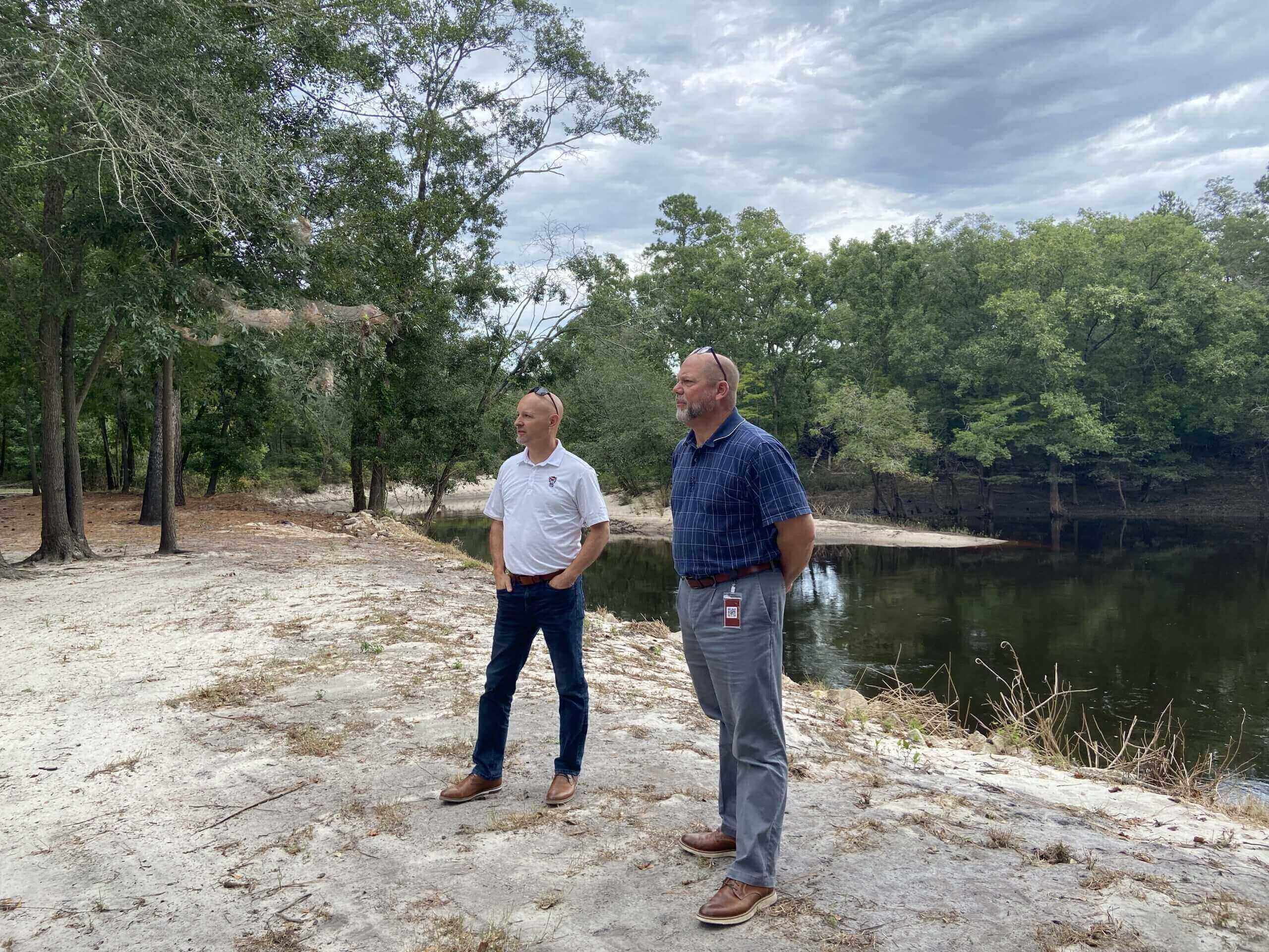 two men standing on edge of body of water